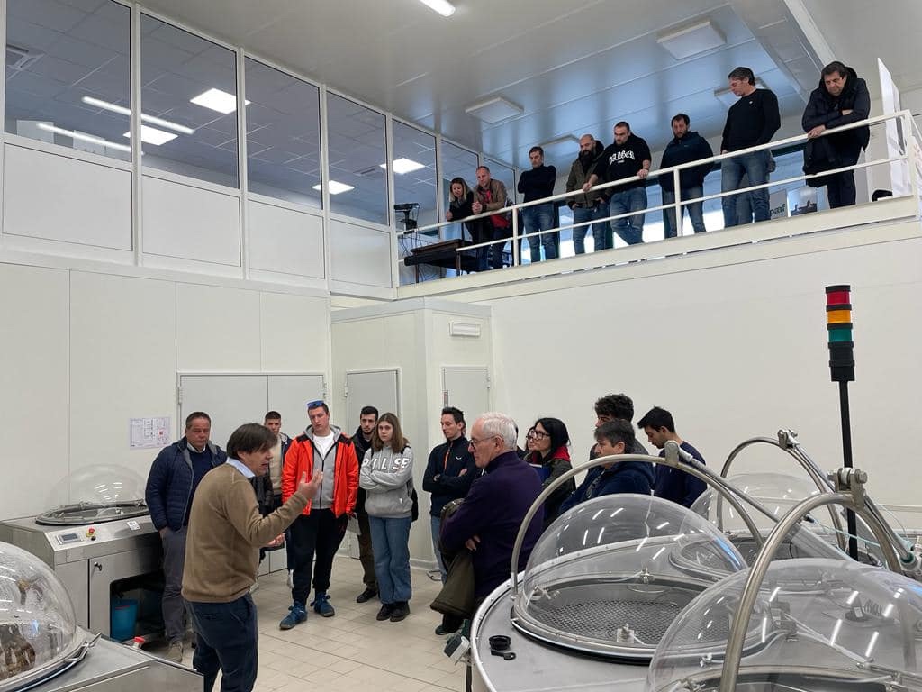 Un groupe de visiteurs dans une salle d’extraction de la bave, avec les dômes Muller au premier plan.
