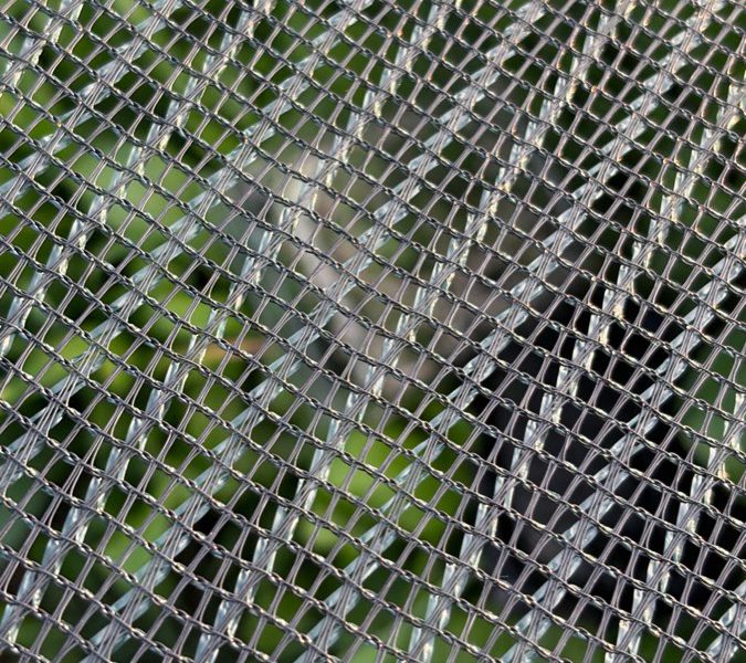 Dettaglio ravvicinato della maglia di una rete di protezione tesa su un recinto.