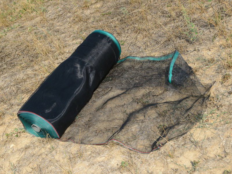 Un rotolo di rete Helitex parzialmente srotolato a terra, prima del montaggio del recinto.