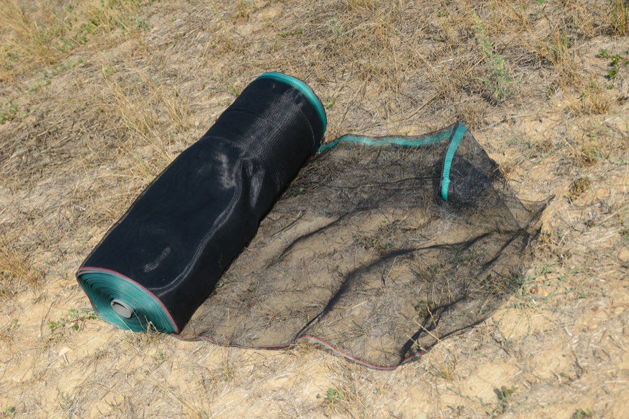 Un rotolo di rete Helitex parzialmente srotolato a terra, prima del montaggio del recinto.